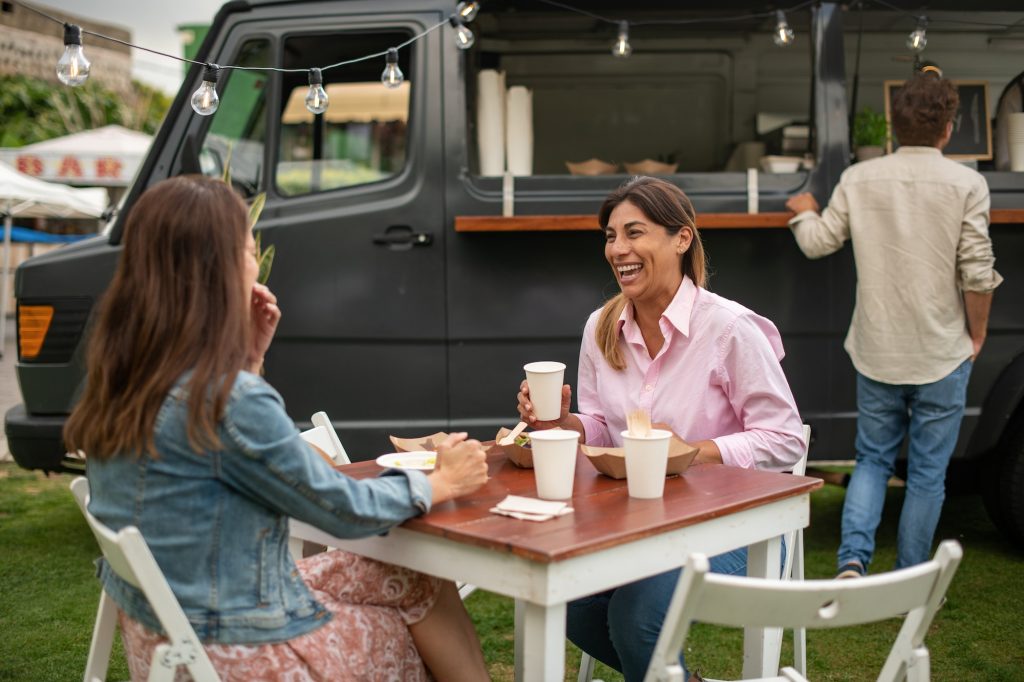 Cheerful women discussing project in street cafe